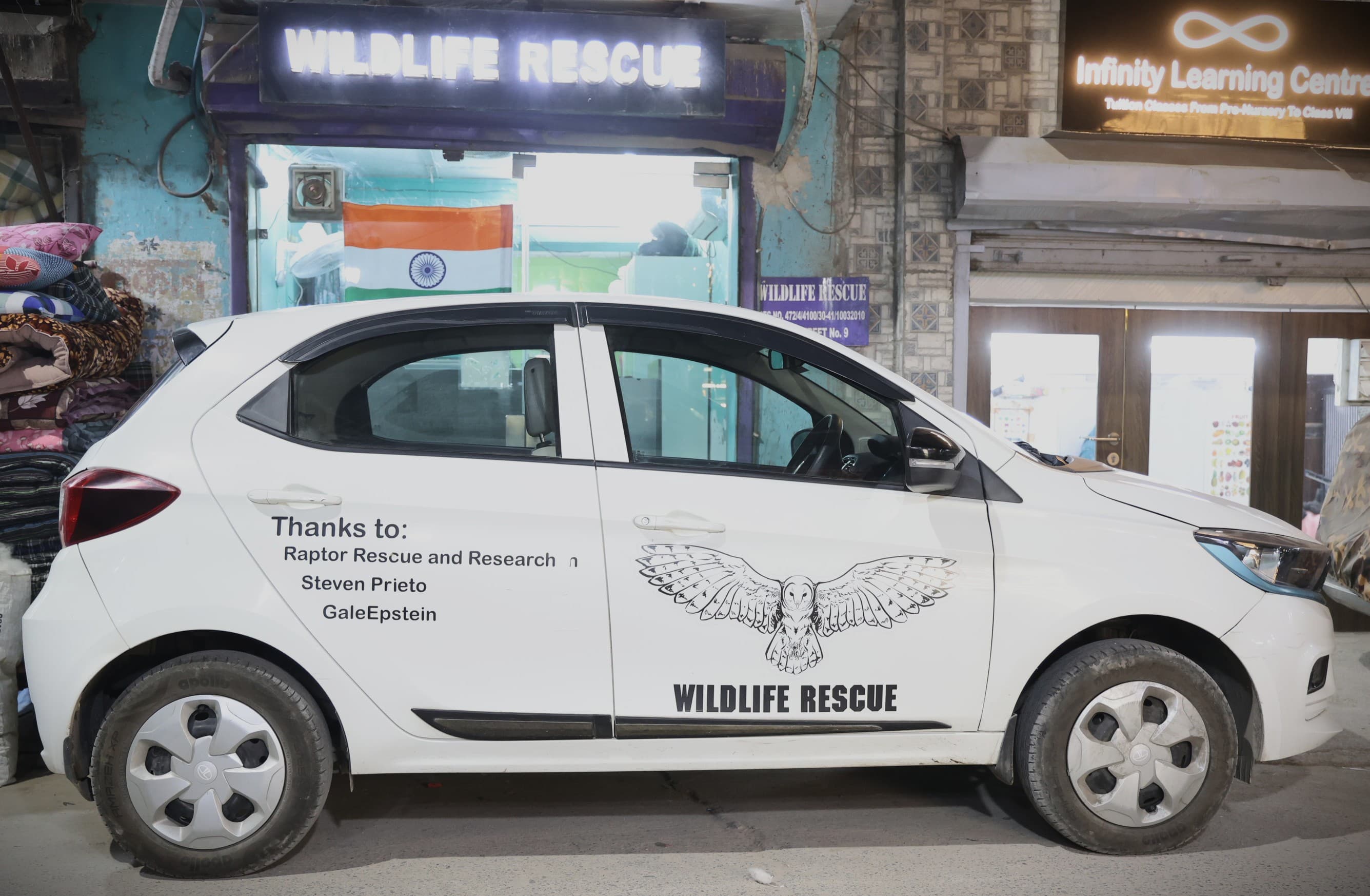 Wildlife Rescue emergency vehicle — Tata EV with owl logo branding, parked outside the rescue center on Street No. 9, Wazirabad Village