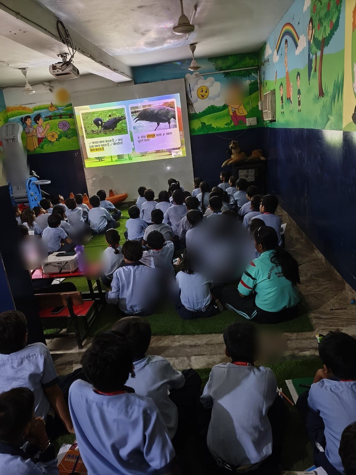 Children watching a bilingual slide comparing what crows do for a city, at a Wildlife Rescue session